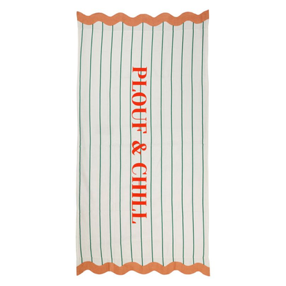 Grande serviette de plage blanche à fines rayures vertes avec l'inscription PLOUF & CHILL en orange et bords ondulés corail.