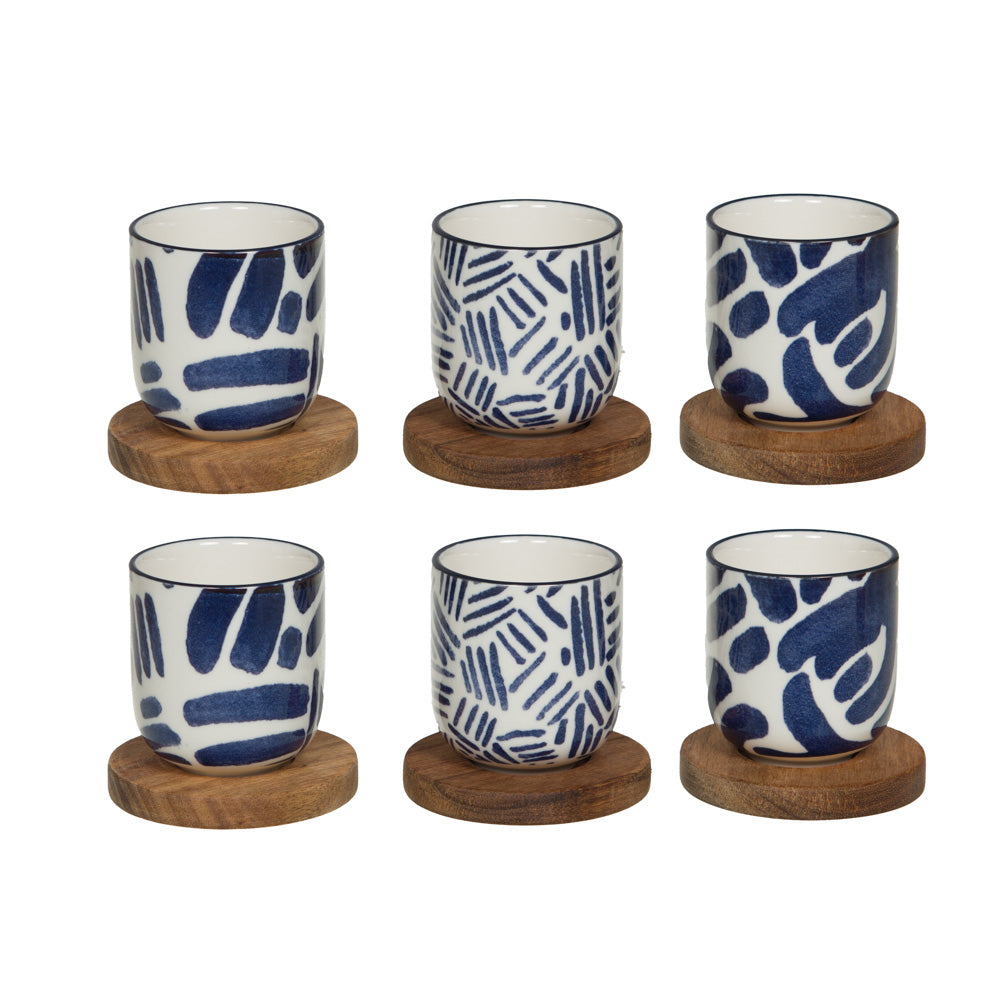 Assortiment de 6 tasses espresso en grès blanc et bleu avec motifs géométriques et leurs sous-tasses rondes en bois naturel.