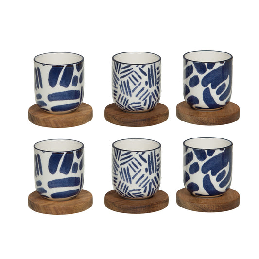 Assortiment de 6 tasses espresso en grès blanc et bleu avec motifs géométriques et leurs sous-tasses rondes en bois naturel.