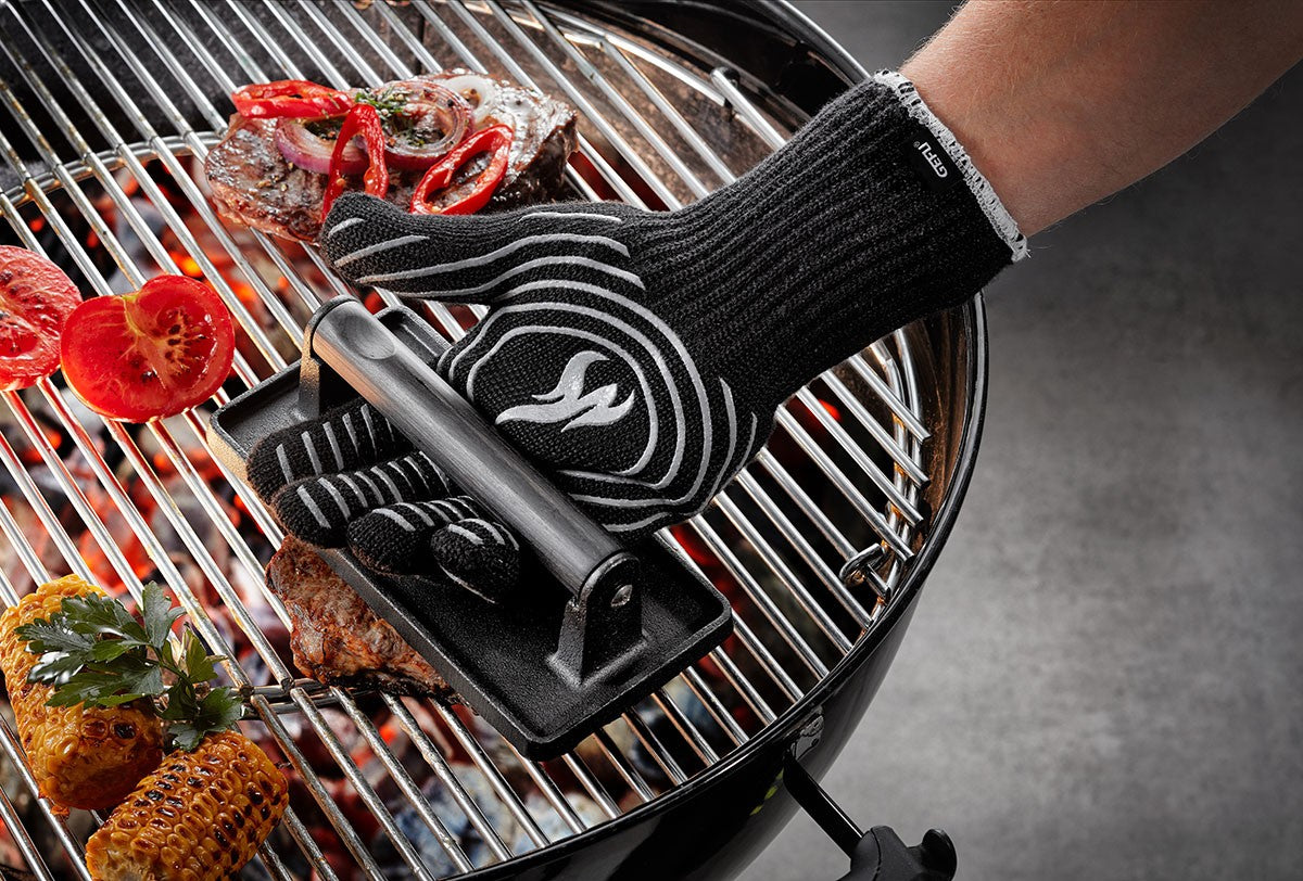 Manipulation d'une grille de barbecue chaude avec le gant de protection haute température