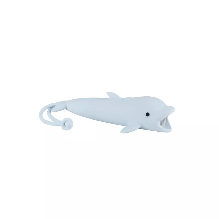 Lampe de poche LED en forme de dauphin bleu ciel en silicone souple sur une table de chevet.