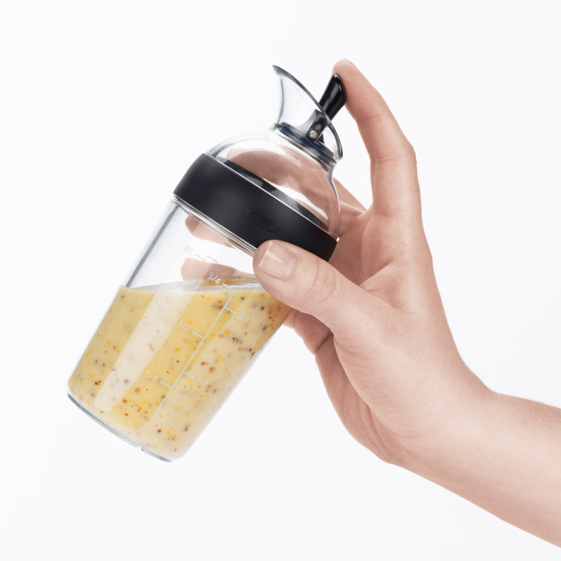 Utilisation du shaker OXO à une main pour verser de la vinaigrette sur une salade sans fuite