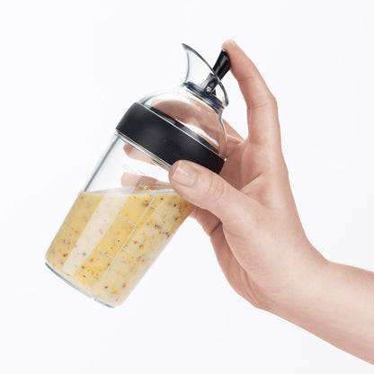 Utilisation du shaker OXO à une main pour verser de la vinaigrette sur une salade sans fuite