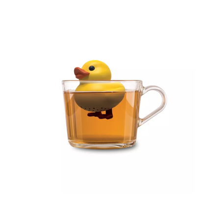 Infuseur à thé flottant en forme de petit canard jaune dans une tasse de thé transparente.