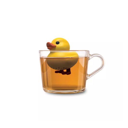 Infuseur à thé flottant en forme de petit canard jaune dans une tasse de thé transparente.